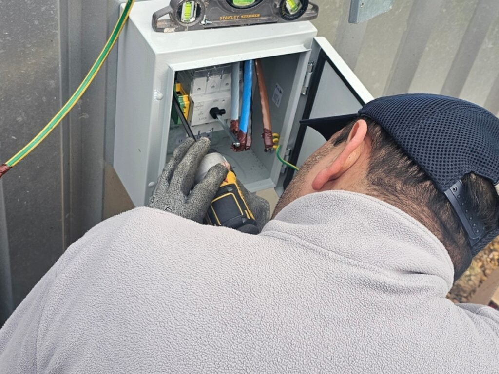 Electrician from Handy Electric Pro carrying out an outdoor electrical installation by terminating heavy-duty electrical cables inside an external electrical enclosure